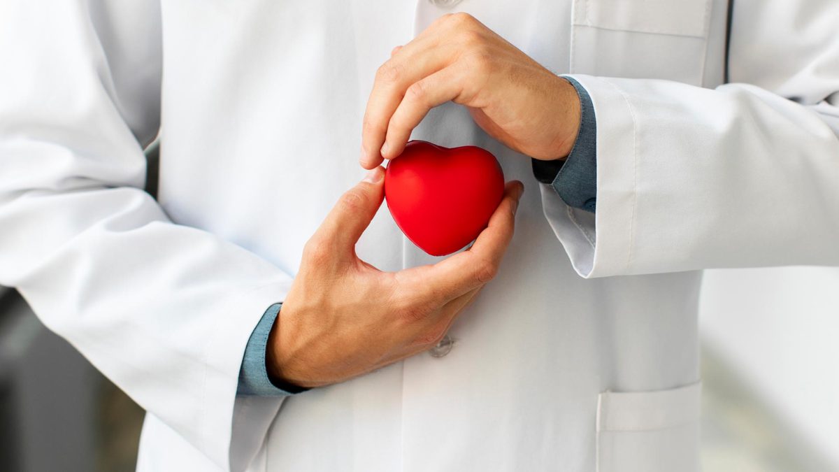 Farmacéutico sostiene un corazón rojo de goma entre sus manos mientras hace un gesto de envolverle